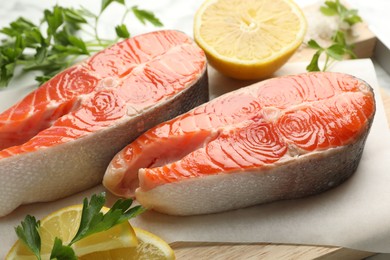 Photo of Seafood. Fresh raw salmon steaks, parsley and pieces of lemon on table, closeup