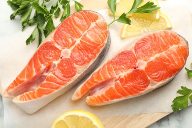 Photo of Seafood. Fresh raw salmon steaks, parsley and pieces of lemon on table, top view