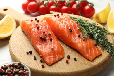 Photo of Seafood. Pieces of salmon fillet, spices, tomatoes and lemon wedges on table, closeup