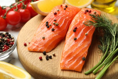 Photo of Seafood. Pieces of salmon fillet, spices, tomatoes and lemon wedges on table, closeup