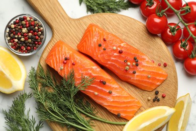 Photo of Seafood. Pieces of salmon fillet, spices, tomatoes and lemon wedges on light table, flat lay