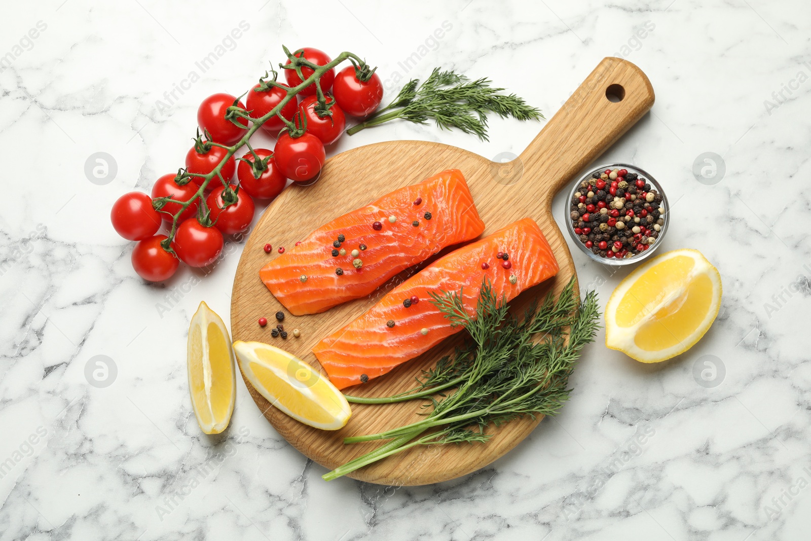 Seafood. Pieces of salmon fillet, spices, tomatoes and lemon wedges on white marble table, flat lay Photo of Seafood. Pieces of salmon fillet, spices, tomatoes and lemon wedges on white marble table, flat lay