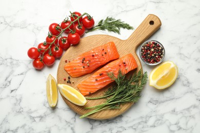 Photo of Seafood. Pieces of salmon fillet, spices, tomatoes and lemon wedges on white marble table, flat lay