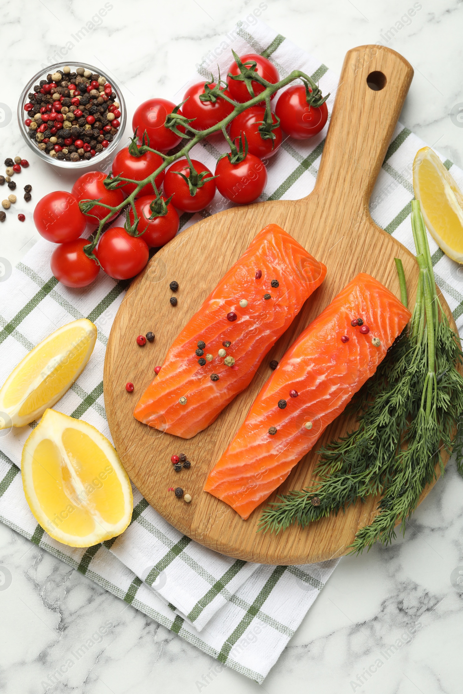 Seafood. Pieces of salmon fillet, spices, tomatoes and lemon wedges on white marble table, flat lay Photo of Seafood. Pieces of salmon fillet, spices, tomatoes and lemon wedges on white marble table, flat lay