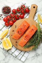Photo of Seafood. Pieces of salmon fillet, spices, tomatoes and lemon wedges on white marble table, flat lay