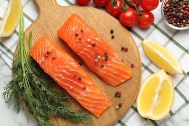 Photo of Seafood. Pieces of salmon fillet, spices, tomatoes and lemon wedges on table, flat lay