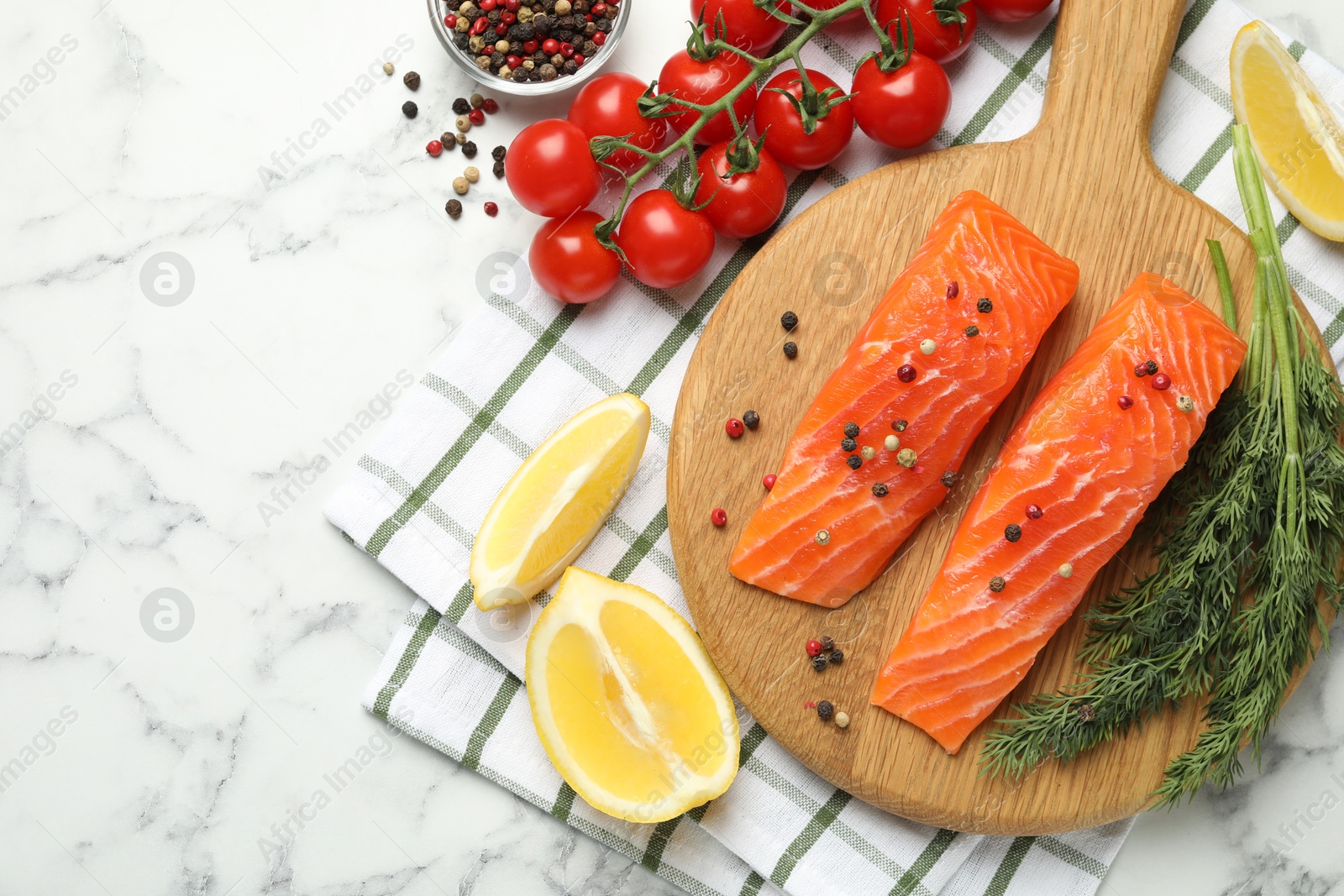 Seafood. Pieces of salmon fillet, spices, tomatoes and lemon wedges on white marble table, flat lay Photo of Seafood. Pieces of salmon fillet, spices, tomatoes and lemon wedges on white marble table, flat lay