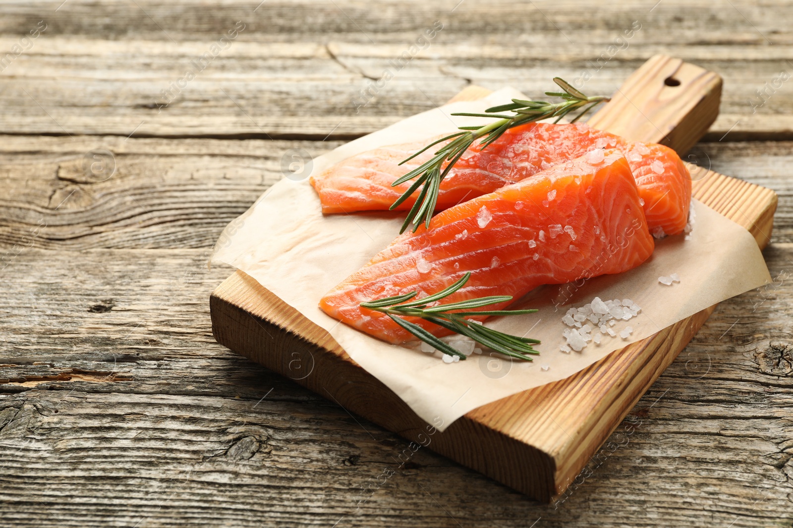 Seafood. Pieces of salmon fillet, rosemary and salt on wooden table Photo of Seafood. Pieces of salmon fillet, rosemary and salt on wooden table