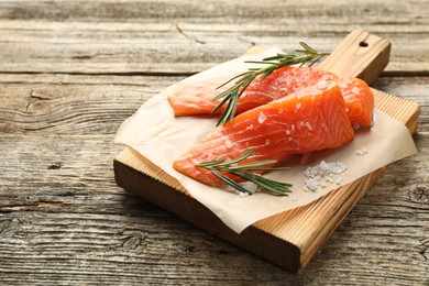 Photo of Seafood. Pieces of salmon fillet, rosemary and salt on wooden table