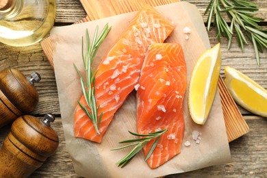Photo of Seafood. Pieces of salmon fillet, spices, oil and lemon wedges on wooden table, flat lay