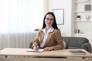Photo of Professional psychologist with clipboard and pen at table in office