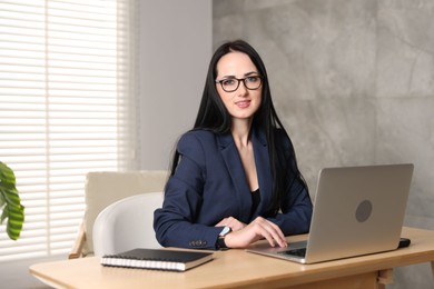 Photo of Professional psychologist working with laptop at table in office