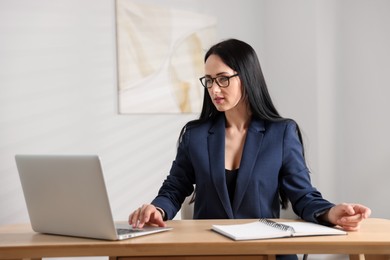Photo of Professional psychologist working with laptop at table in office