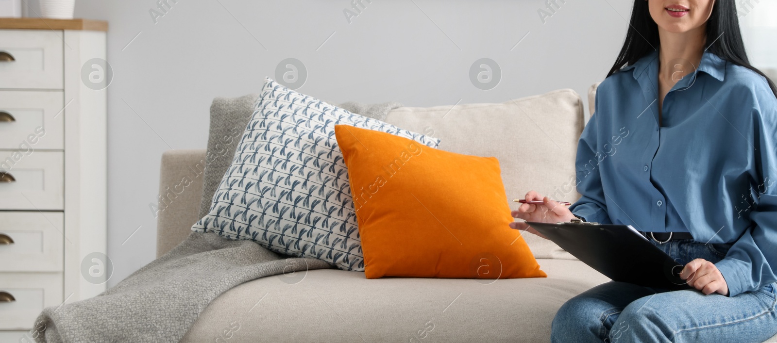 Professional psychologist with clipboard and pen on sofa in office, closeup Photo of Professional psychologist with clipboard and pen on sofa in office, closeup
