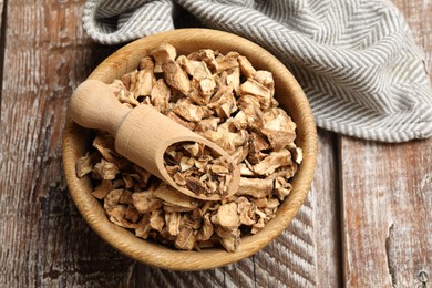 Photo of Pieces of dry chicory roots in bowl and scoop on wooden table, top view