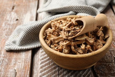 Photo of Pieces of dry chicory roots in bowl and scoop on wooden table, closeup