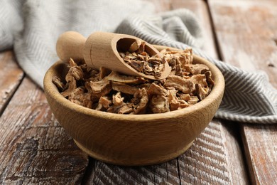 Photo of Pieces of dry chicory roots in bowl and scoop on wooden table, closeup