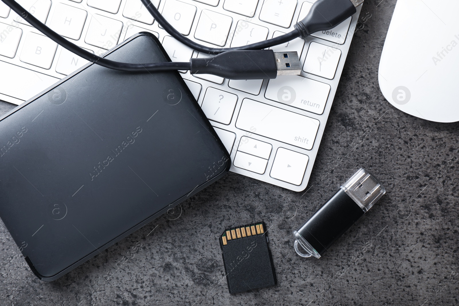 SD memory card, USB flash drive, hard disk drive with cable and keyboard on dark grey table, flat lay Photo of SD memory card, USB flash drive, hard disk drive with cable and keyboard on dark grey table, flat lay