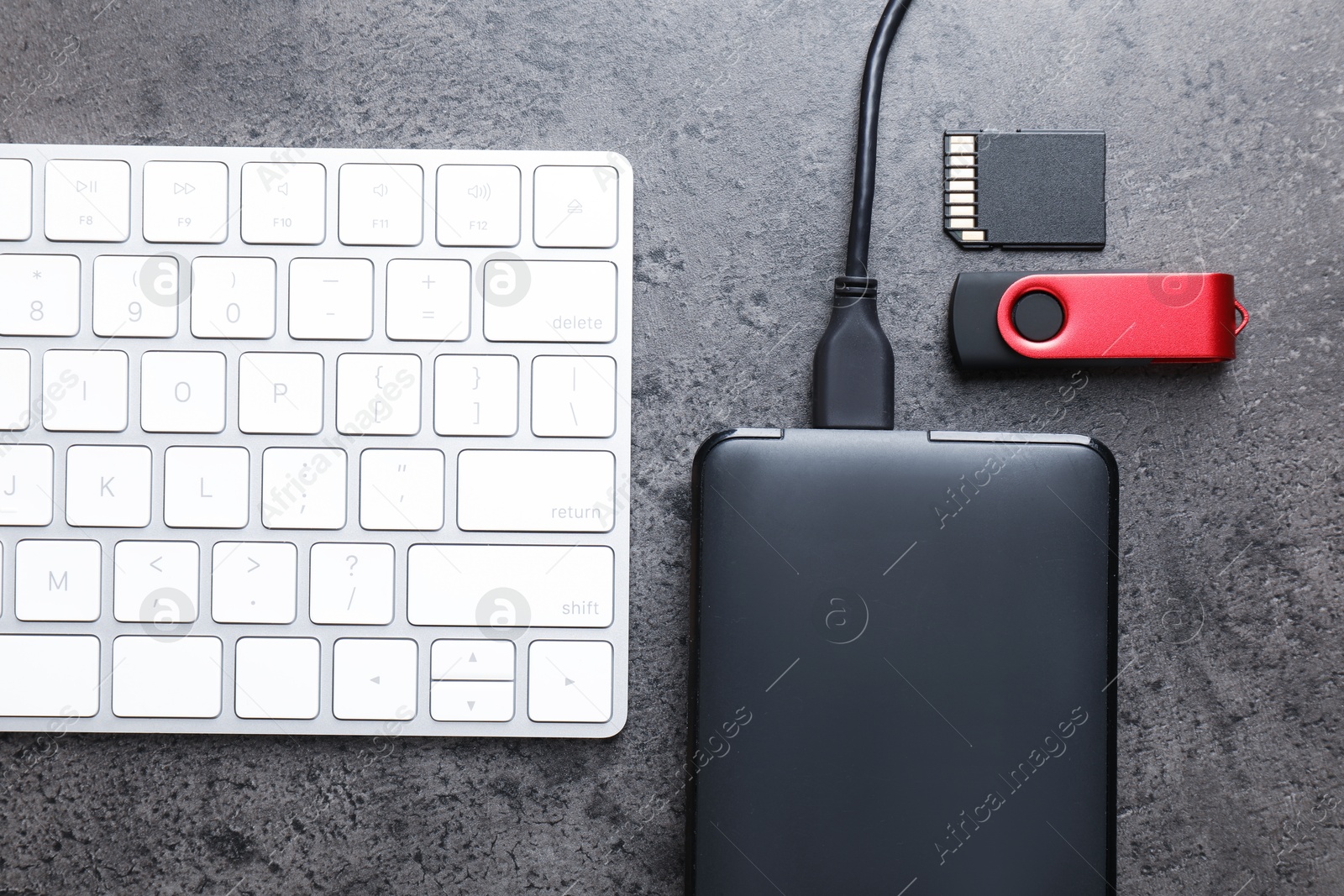SD memory card, USB flash drive, hard disk drive with cable and keyboard on dark grey table, flat lay Photo of SD memory card, USB flash drive, hard disk drive with cable and keyboard on dark grey table, flat lay