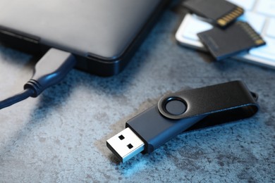 Photo of SD memory cards, USB flash drive, hard disk drive with cable and keyboard on dark grey table, closeup