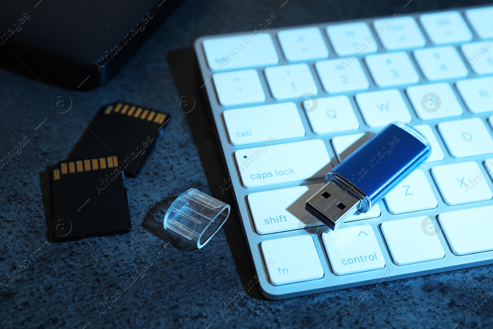 SD memory cards, USB flash drive and keyboard on dark grey table, closeup Photo of SD memory cards, USB flash drive and keyboard on dark grey table, closeup