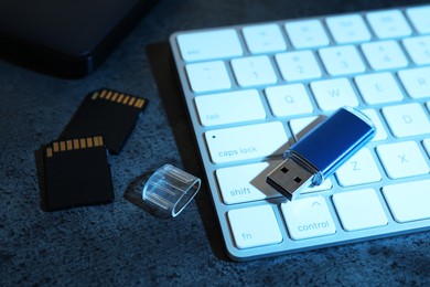 Photo of SD memory cards, USB flash drive and keyboard on dark grey table, closeup