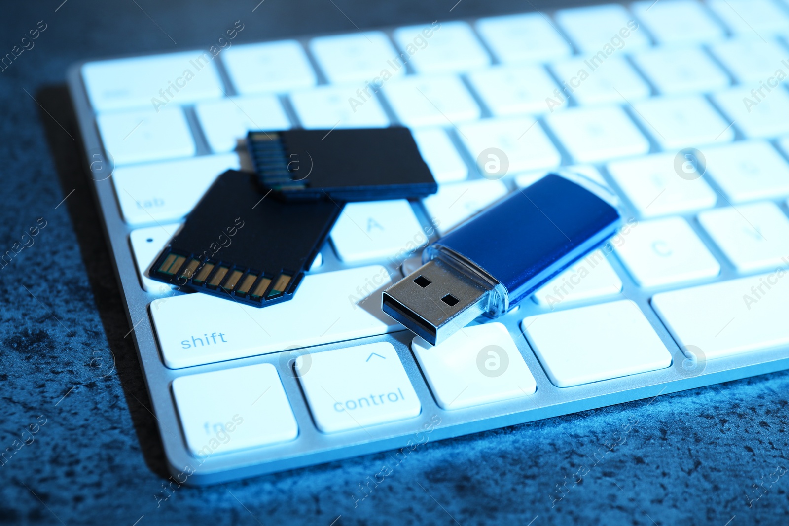 SD memory cards, USB flash drive and keyboard on dark grey table, closeup Photo of SD memory cards, USB flash drive and keyboard on dark grey table, closeup