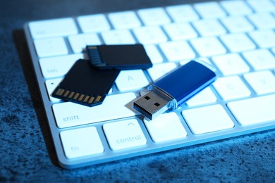 Photo of SD memory cards, USB flash drive and keyboard on dark grey table, closeup
