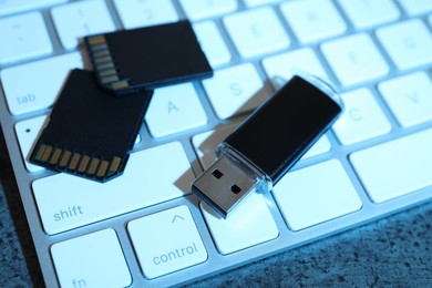 Photo of SD memory cards, USB flash drive and keyboard on dark grey table, closeup
