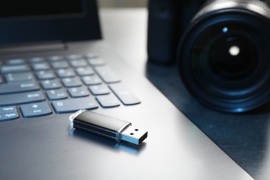 Photo of USB flash drive, camera and laptop on dark grey table, closeup