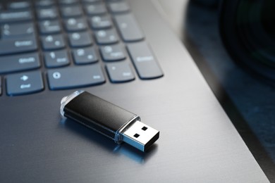 Photo of USB flash drive and laptop on dark grey table, closeup