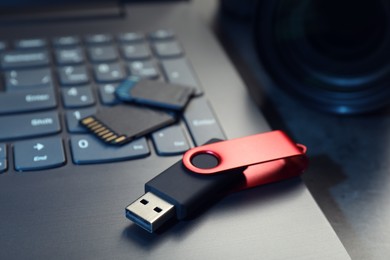 Photo of SD memory cards, USB flash drive and laptop on dark grey table, closeup
