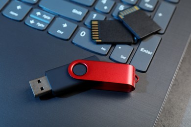 Photo of SD memory cards, USB flash drive and laptop on dark grey table, closeup