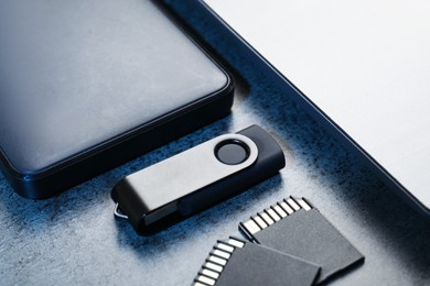 Photo of SD memory cards, USB flash drive, hard disk drive and laptop on dark grey table, closeup