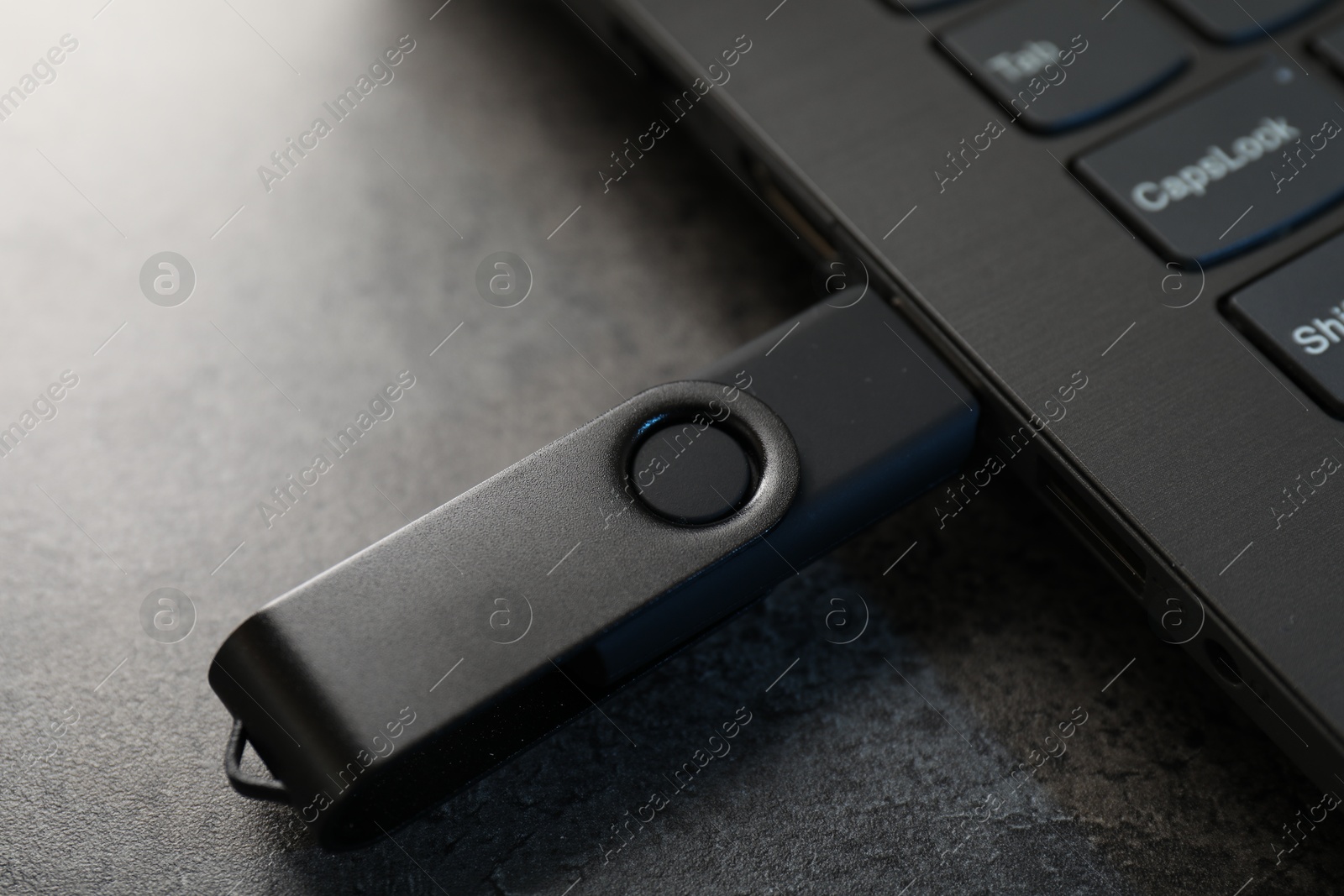USB flash drive connected to laptop on dark grey table, closeup Photo of USB flash drive connected to laptop on dark grey table, closeup