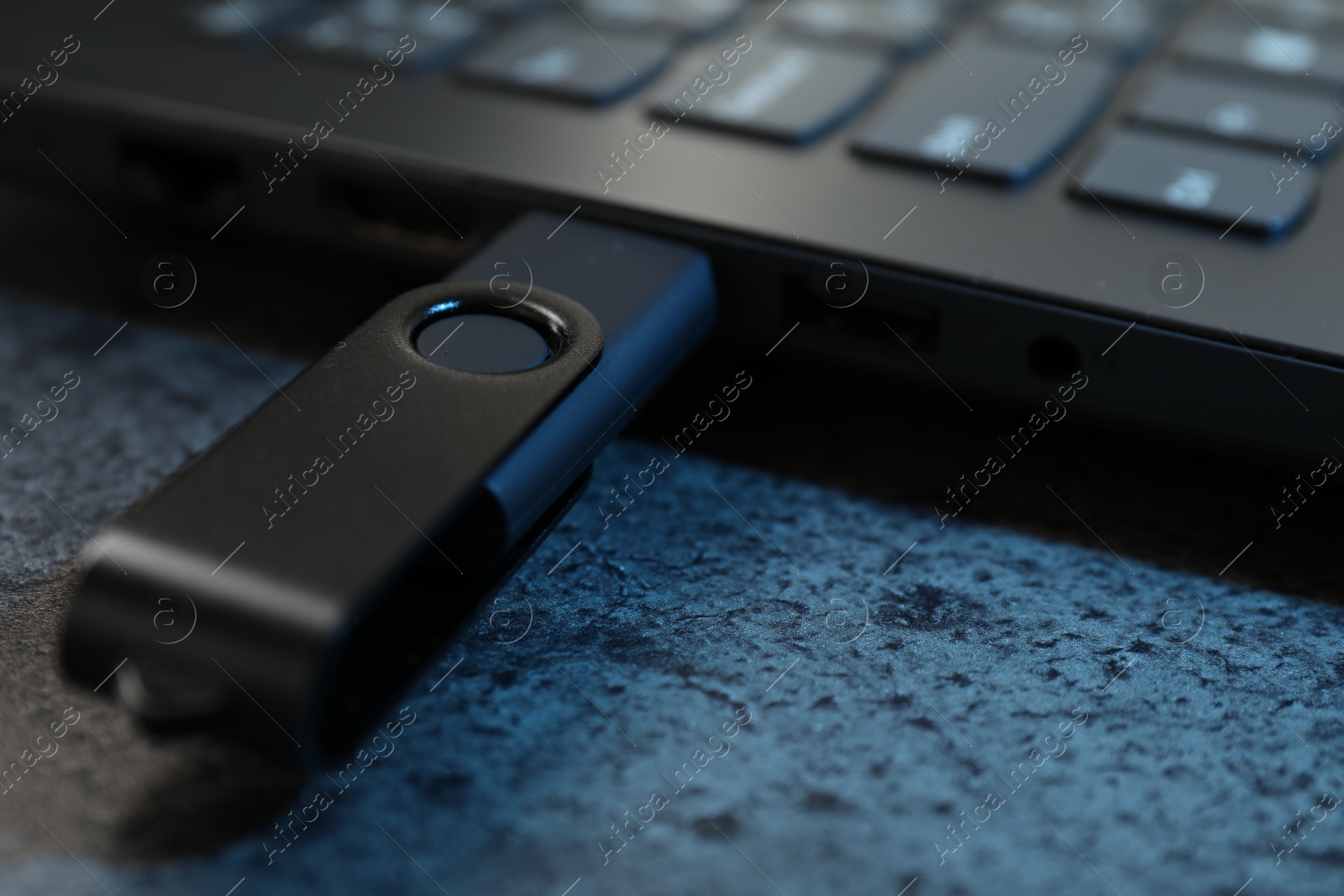 USB flash drive connected to laptop on dark grey table, closeup Photo of USB flash drive connected to laptop on dark grey table, closeup