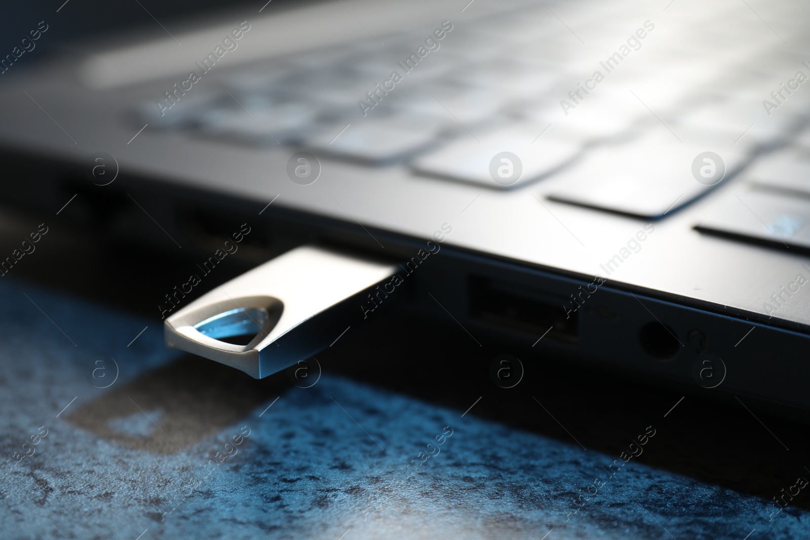 USB flash drive connected to laptop on dark grey table, closeup Photo of USB flash drive connected to laptop on dark grey table, closeup