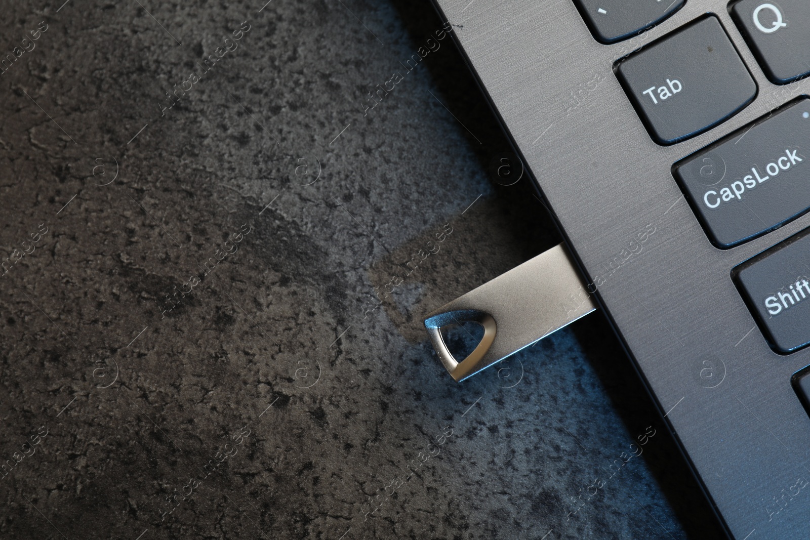 USB flash drive connected to laptop on dark grey table, top view. Space for text Photo of USB flash drive connected to laptop on dark grey table, top view. Space for text