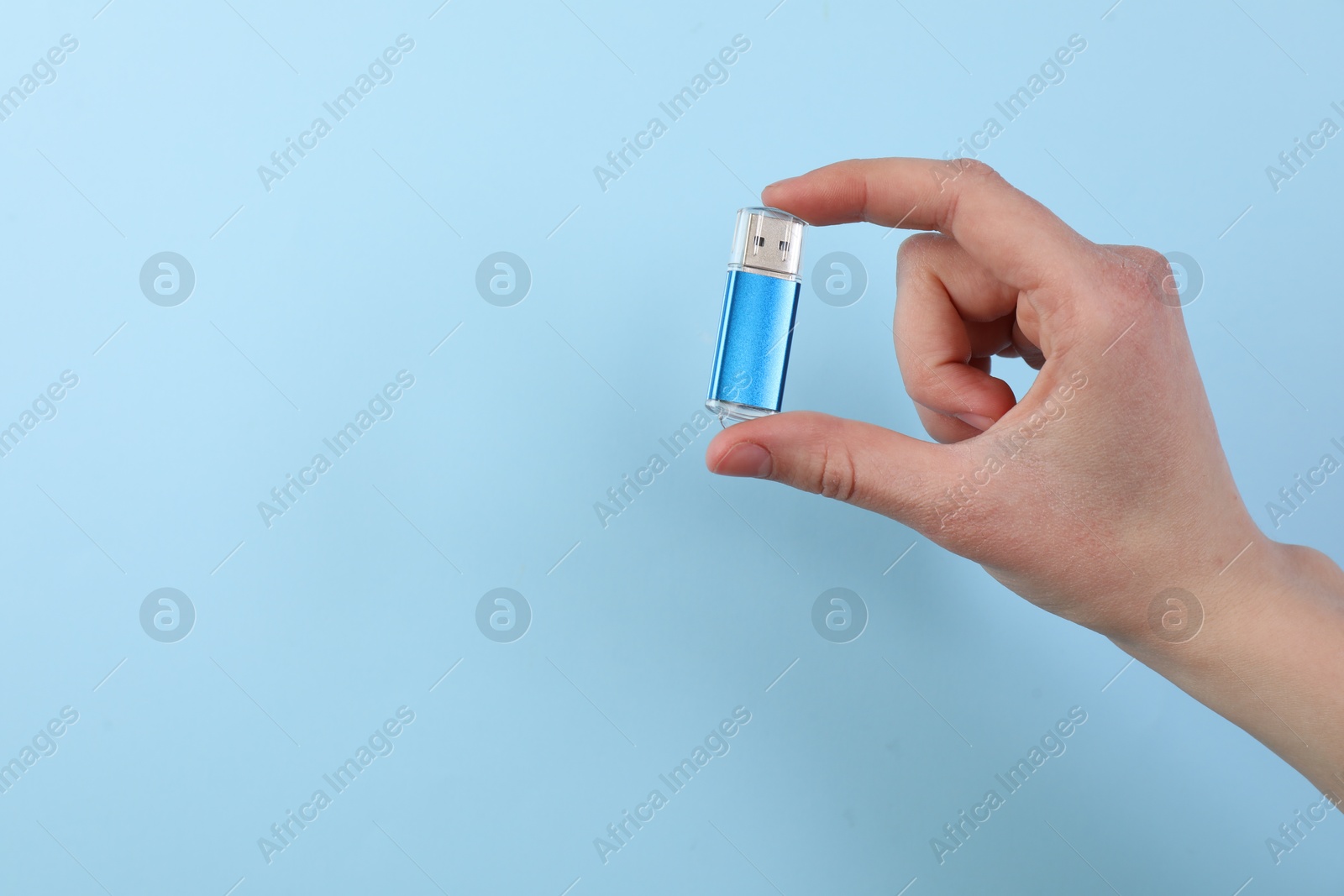 Woman holding USB flash drive on light blue background, closeup. Space for text Photo of Woman holding USB flash drive on light blue background, closeup. Space for text