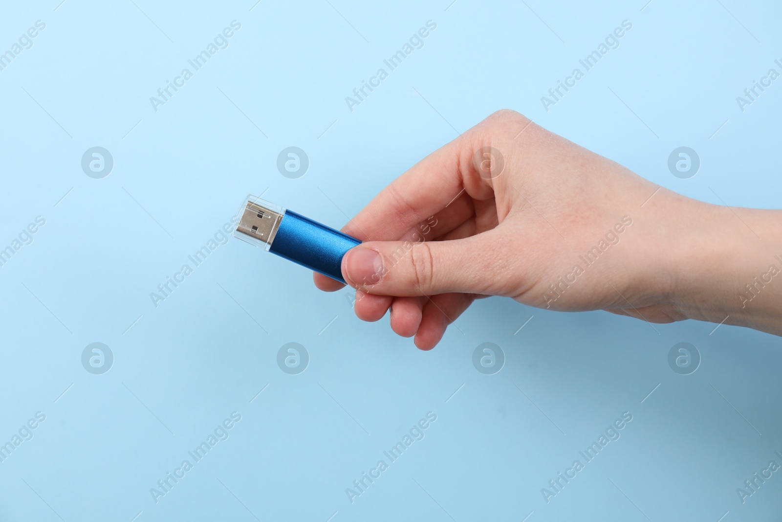Woman holding USB flash drive on light blue background, closeup Photo of Woman holding USB flash drive on light blue background, closeup