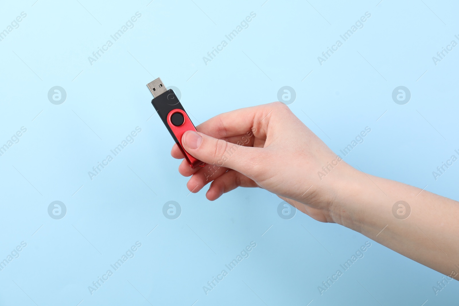 Woman holding USB flash drive on light blue background, closeup Photo of Woman holding USB flash drive on light blue background, closeup