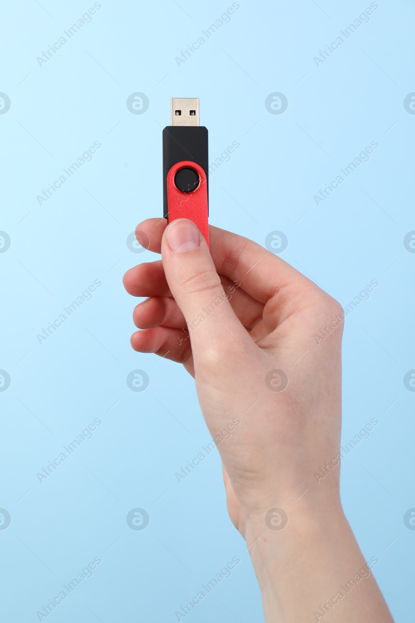 Woman holding USB flash drive on light blue background, closeup Photo of Woman holding USB flash drive on light blue background, closeup