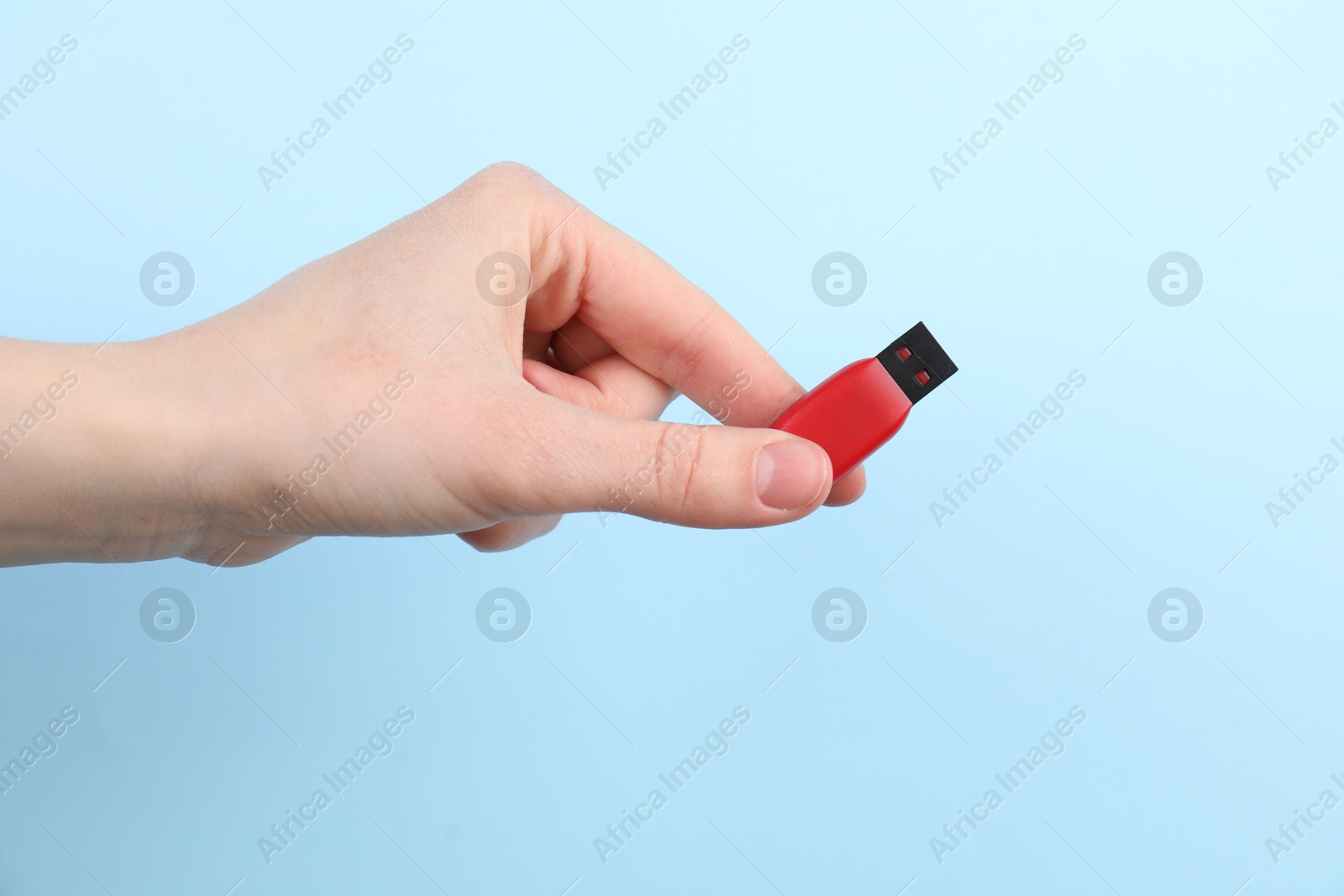 Woman holding USB flash drive on light blue background, closeup Photo of Woman holding USB flash drive on light blue background, closeup