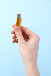 Photo of Woman holding USB flash drive on light blue background, closeup