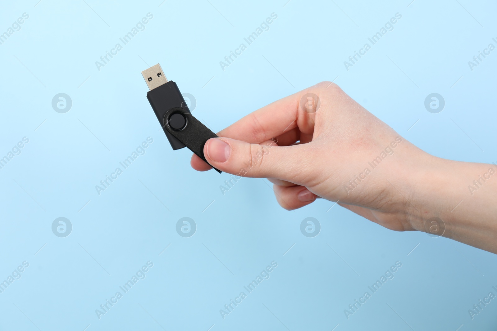 Woman holding USB flash drive on light blue background, closeup Photo of Woman holding USB flash drive on light blue background, closeup