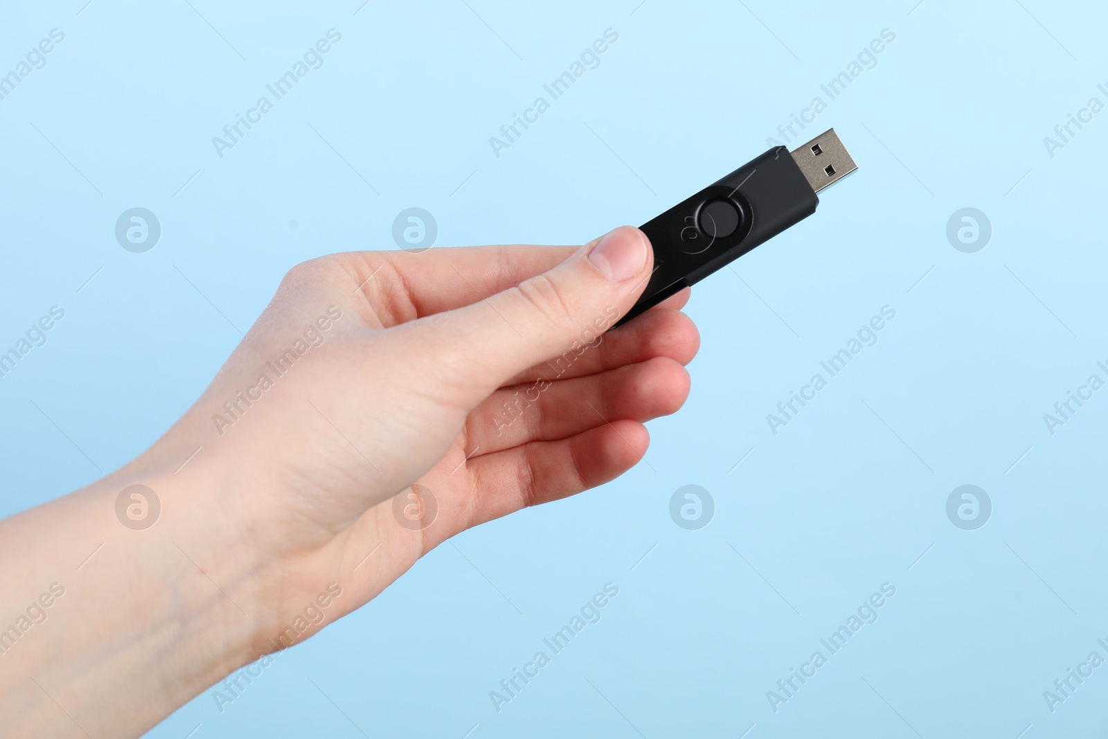 Woman holding USB flash drive on light blue background, closeup Photo of Woman holding USB flash drive on light blue background, closeup
