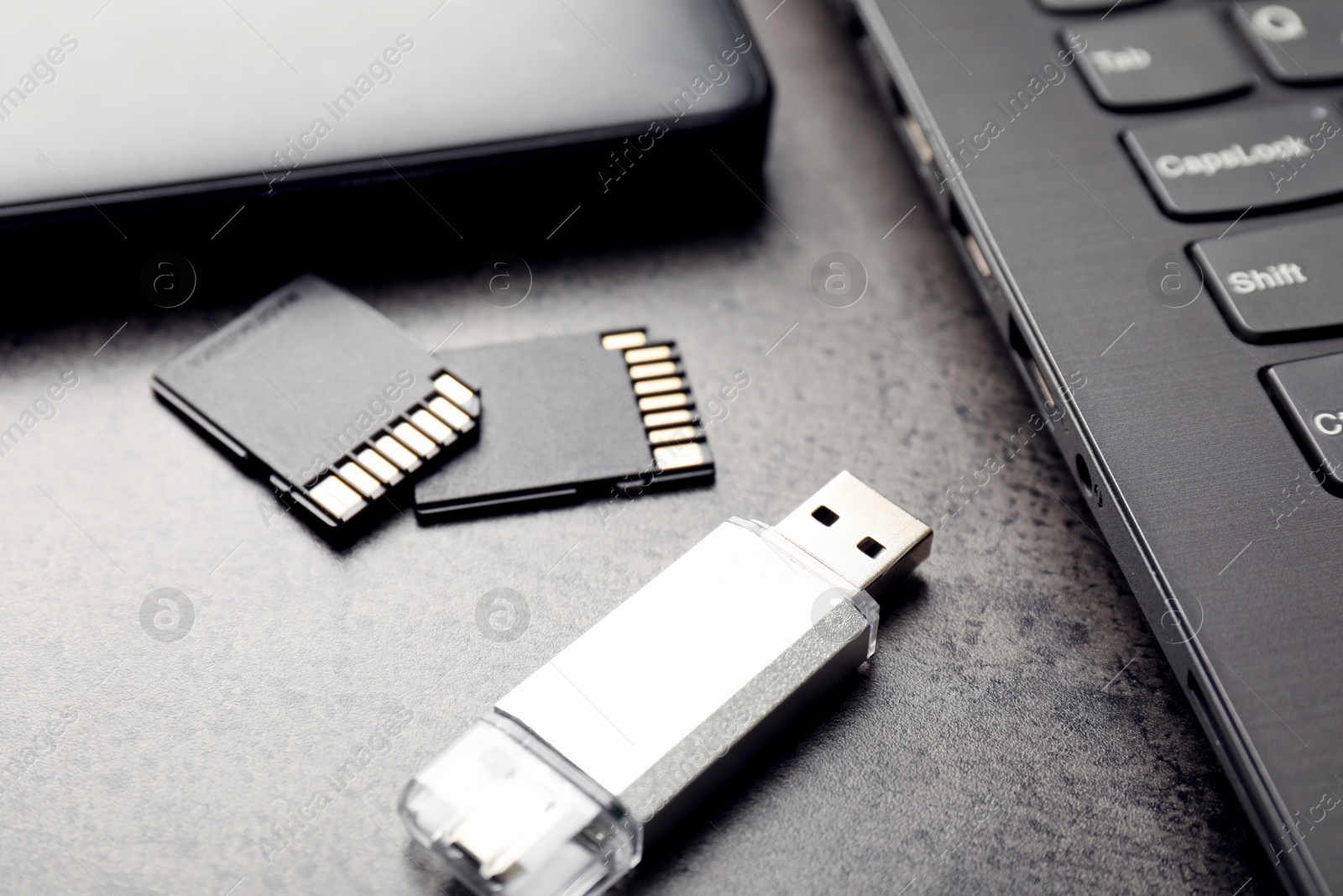 SD memory cards, USB flash drive, hard disk drive and laptop on dark grey table, closeup Photo of SD memory cards, USB flash drive, hard disk drive and laptop on dark grey table, closeup