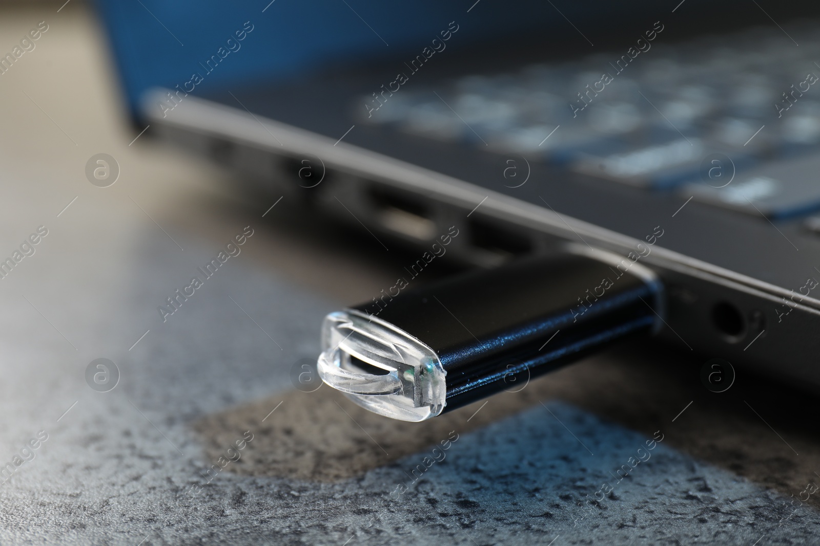 USB flash drive connected to laptop on dark grey table, closeup Photo of USB flash drive connected to laptop on dark grey table, closeup