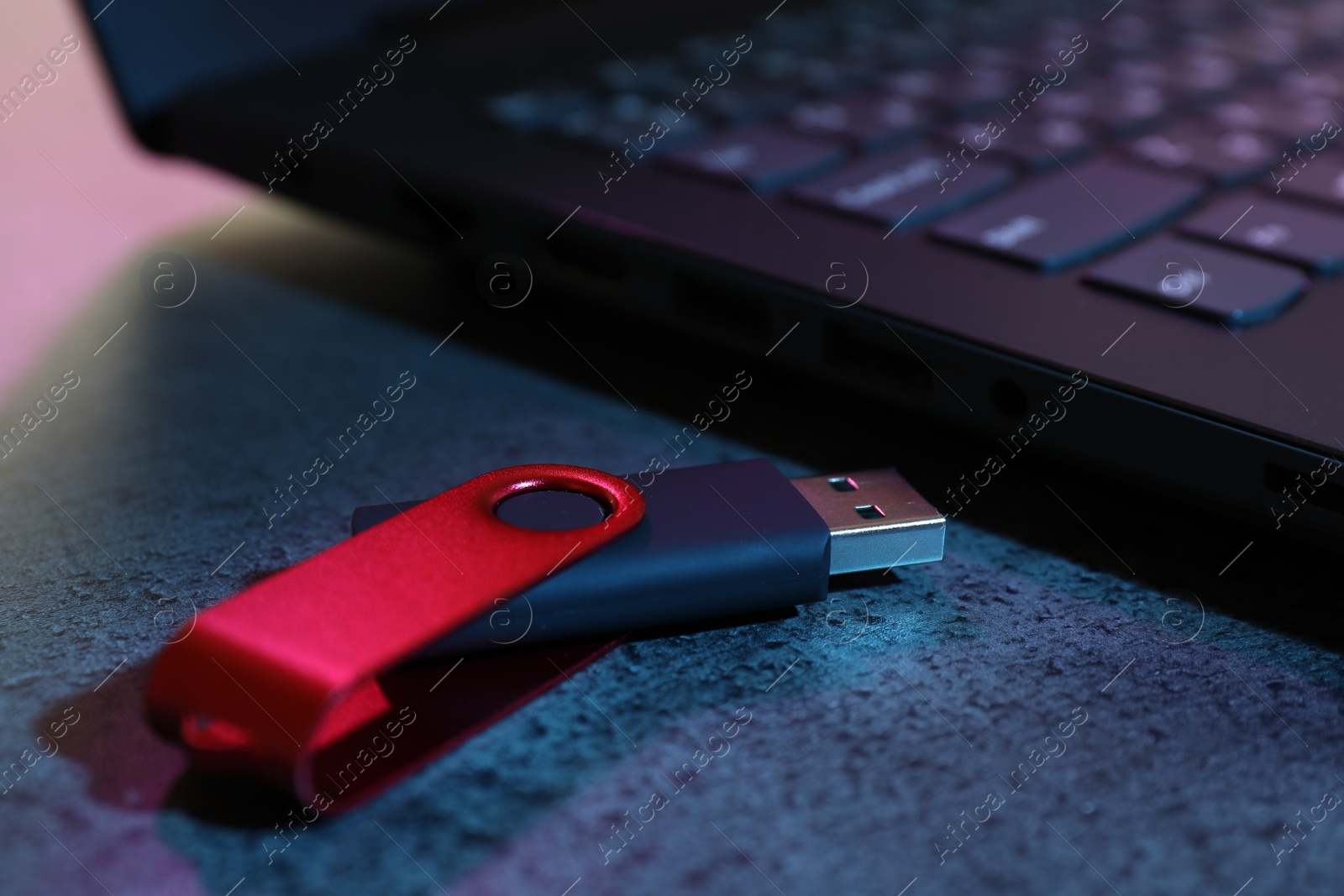 USB flash drive and laptop on dark grey table, closeup Photo of USB flash drive and laptop on dark grey table, closeup