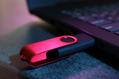 Photo of USB flash drive connected to laptop on dark grey table, closeup
